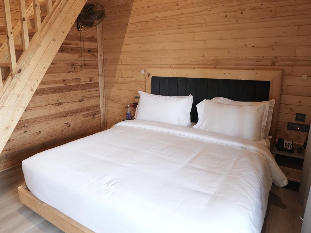 Deluxe Cottage bedroom with wooden staircase to the loft