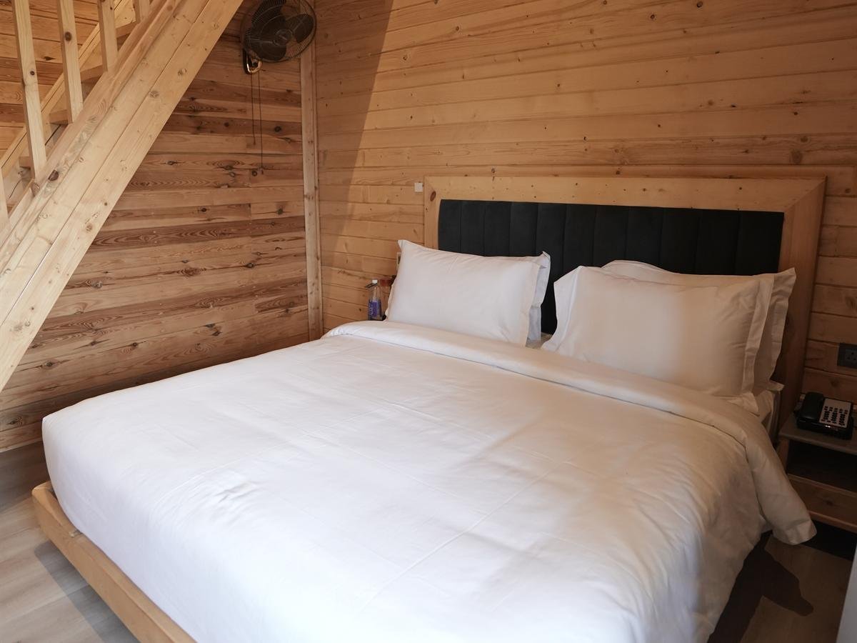 Deluxe Cottage king-size bed beneath exposed rafters